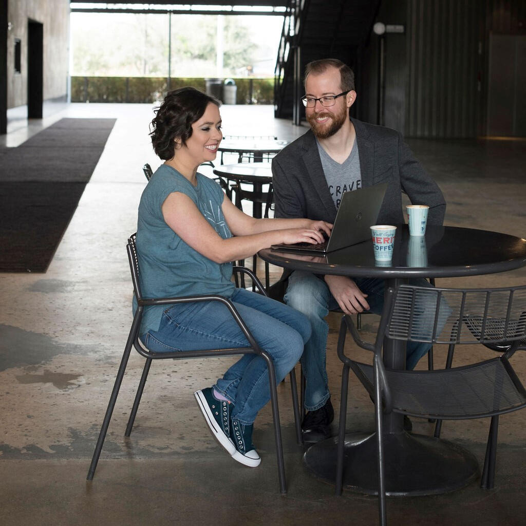 Megan works on her laptop while Travis looks at her smiling